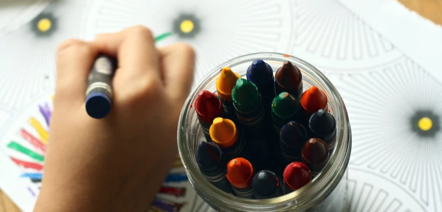 An image of a kid coloring with crayons