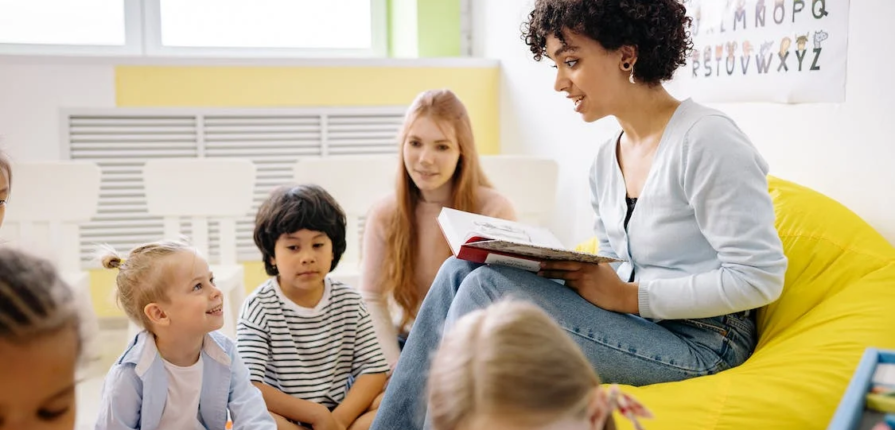An image of a woman reading a book to the kids
