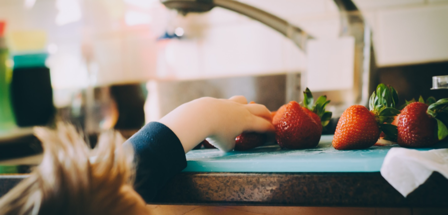 Kid taking strawberries from the kitchen counter