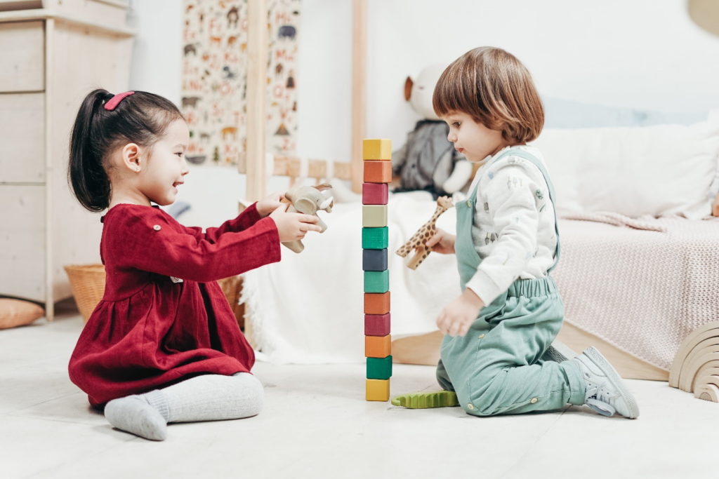 Two toddlers joyfully stacking blocks in a Montessori-inspired home environment, showing the importance of choosing the right infant and toddler toys.