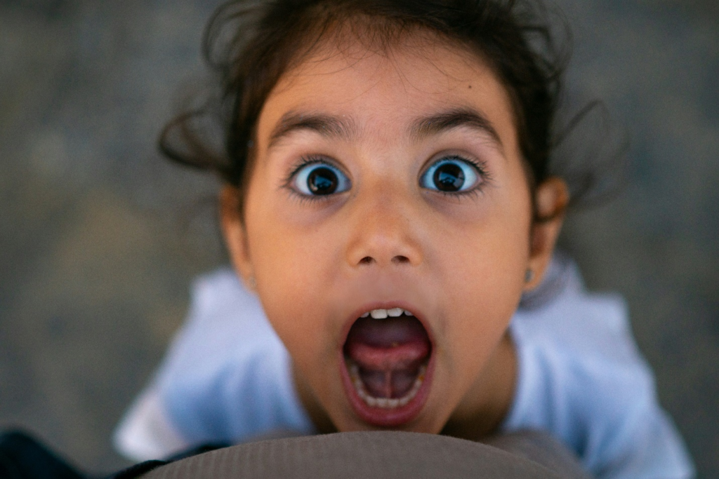Child looking up with eyes wide and mouth open as if to yell, depicting anger in children 