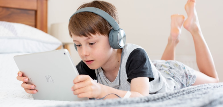A boy using an iPad with headphones on
